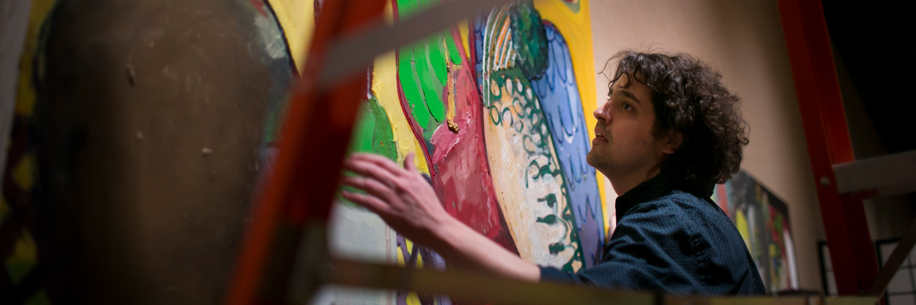 A student is placing artwork on a wall.