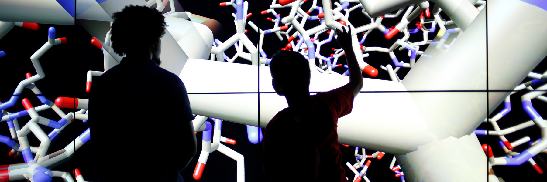 Two people standing in front of an large interactive screen