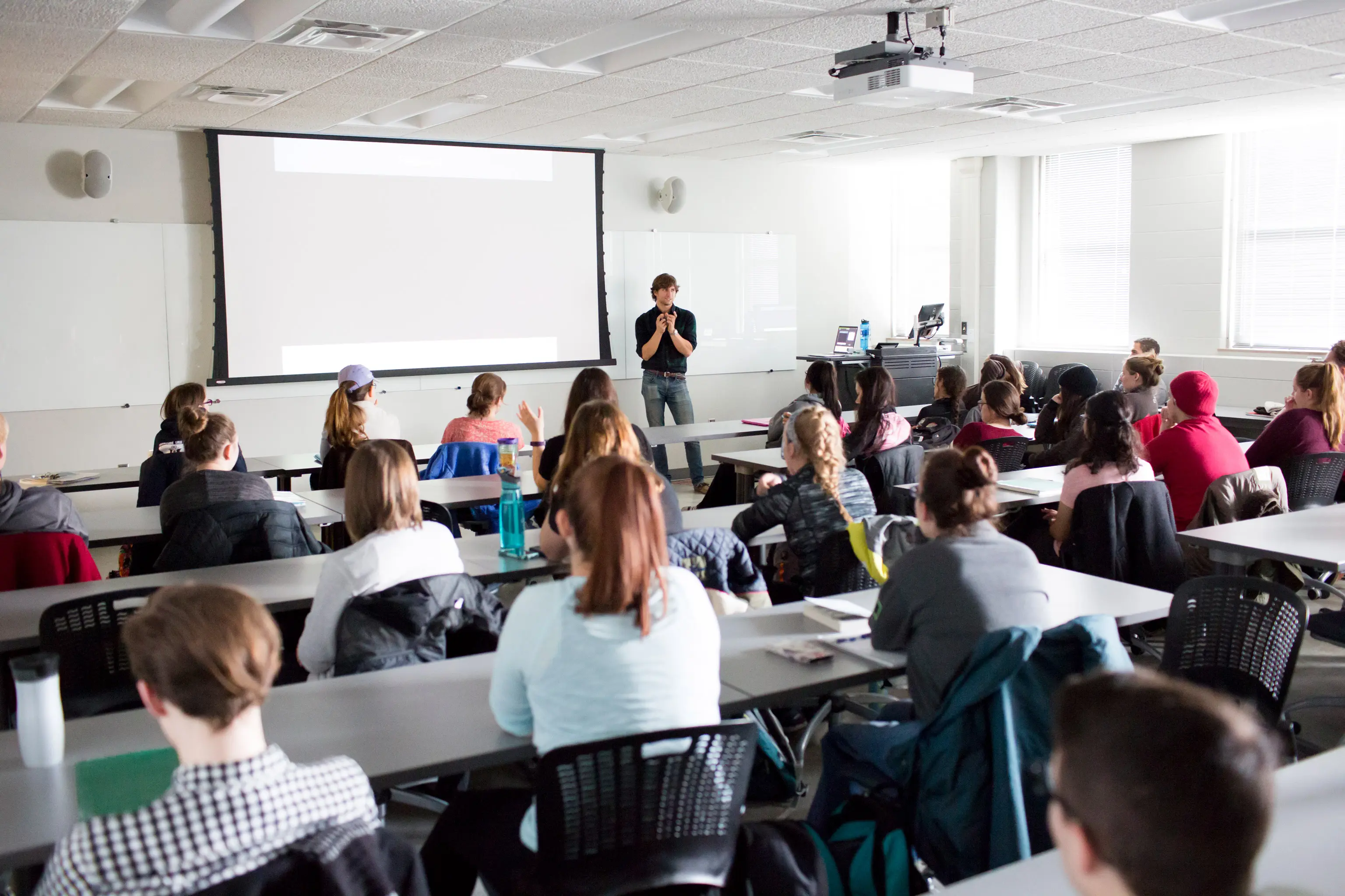 A man lectures in front of a classroom of students.