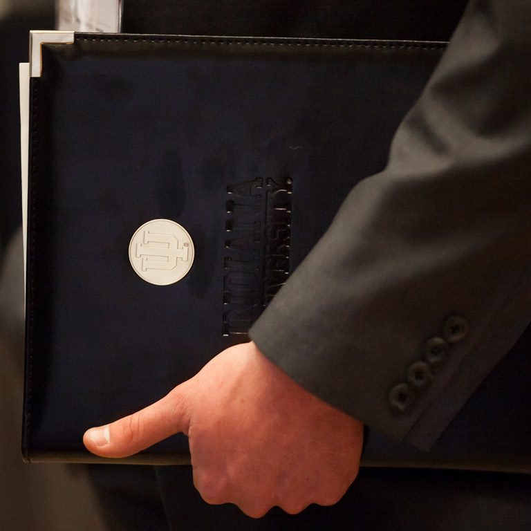 A student's arm around a leather notebook at a career fair.